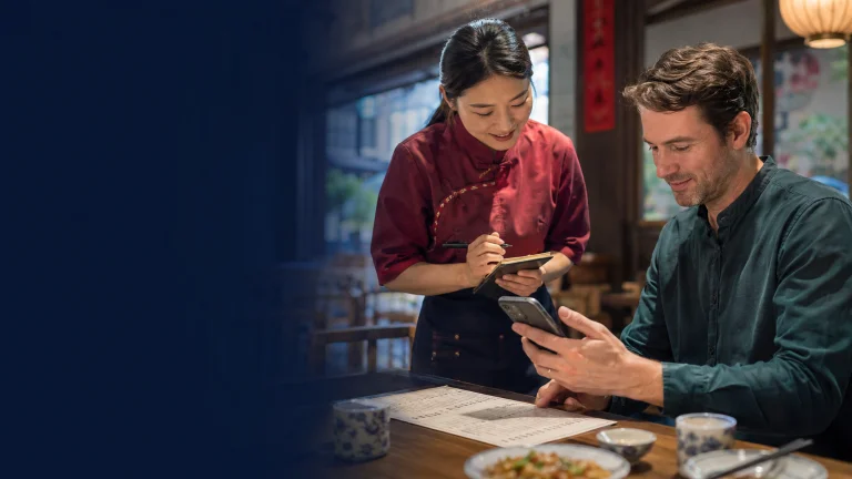 International visitor using a phone translation app with a Chinese restaurant server